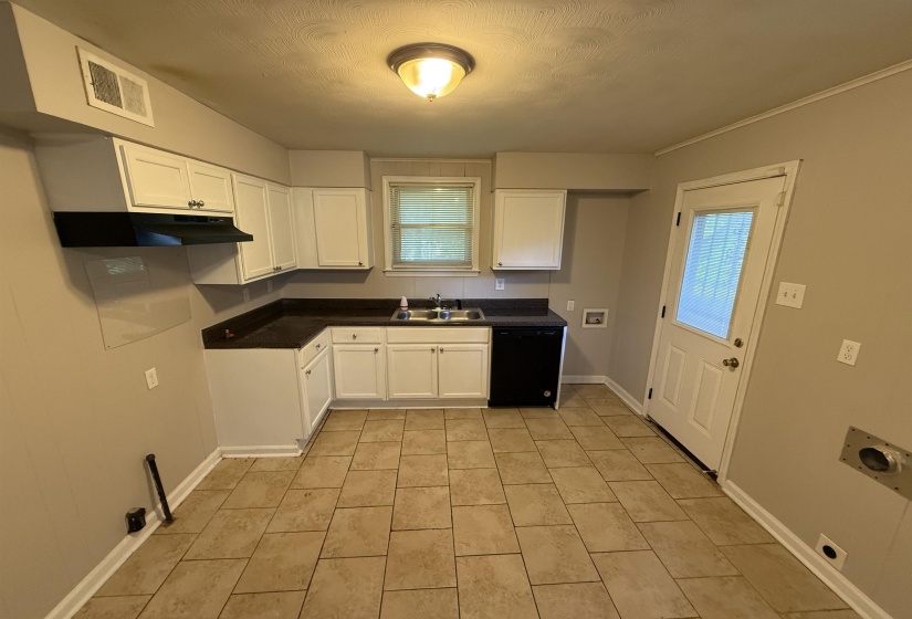 Kitchen featuring white cabinetry, dark countertops, a stainless steel double basin sink, and a black dishwasher