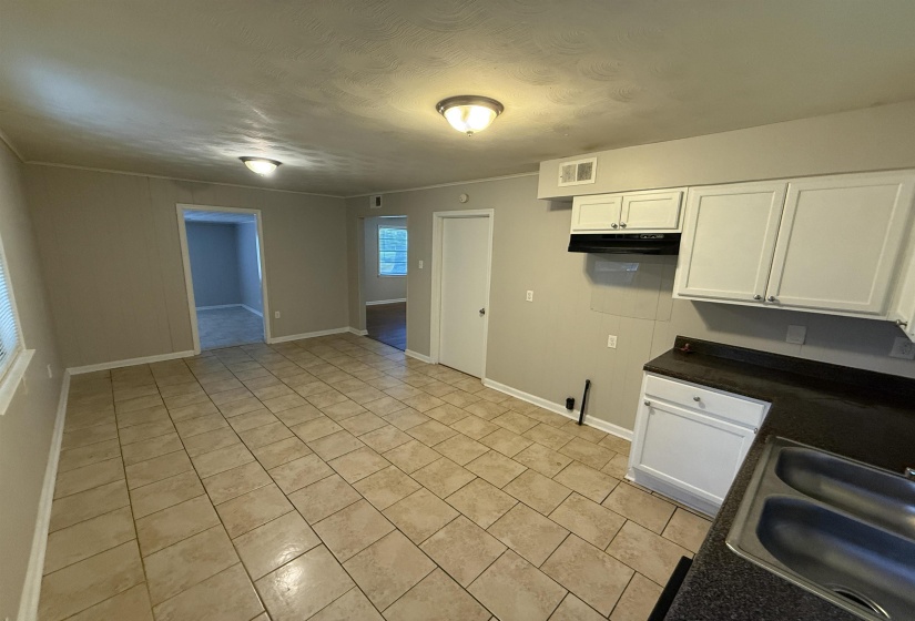 Open-concept living space featuring tiled flooring, neutral wall paint, white trim, and flush-mount lighting