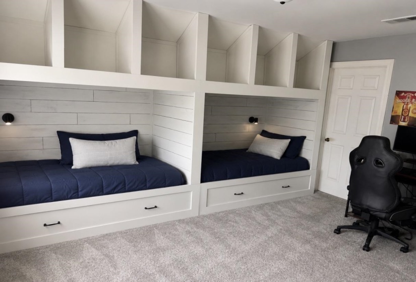 Built-in bunk beds with integrated storage drawers and individual sconce lighting