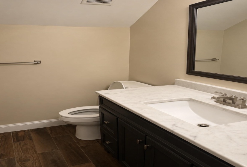 Bathroom vanity featuring a white undermount sink, a stone-finish countertop, and a dark wood-finish cabinet with brushed nickel hardware