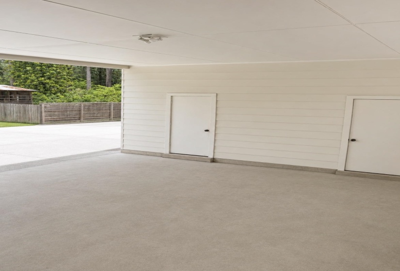 Covered outdoor area featuring a smooth concrete floor, horizontal siding, and built-in storage doors