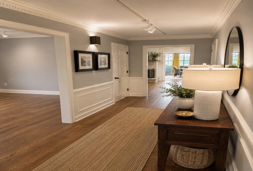 Spacious interior hallway featuring wood-finish flooring, wainscoting, and crown molding