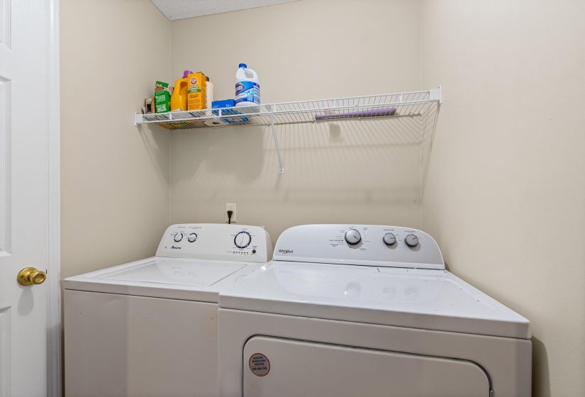 Dedicated laundry area featuring a white washing machine and dryer, a white wire shelving unit for storage, and neutral wall paint