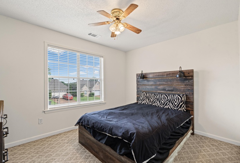 Bright room featuring a large window with horizontal blinds, a ceiling fan with light fixture, and patterned carpeting