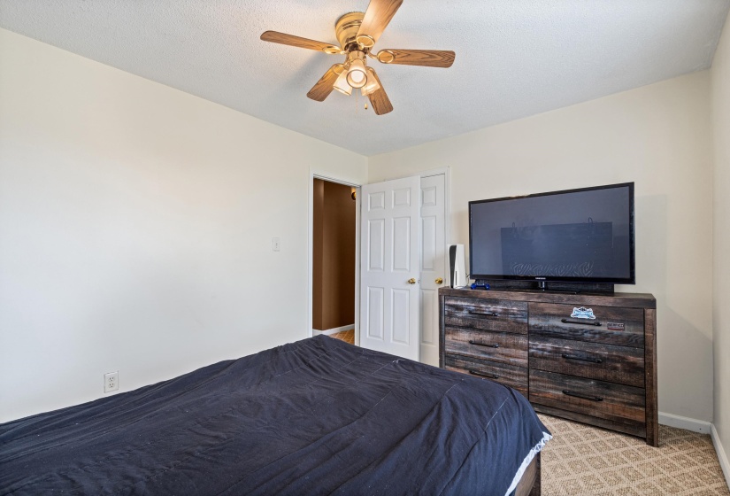 Carpeted room featuring a ceiling fan with integrated lighting, a white painted door, and light-colored walls