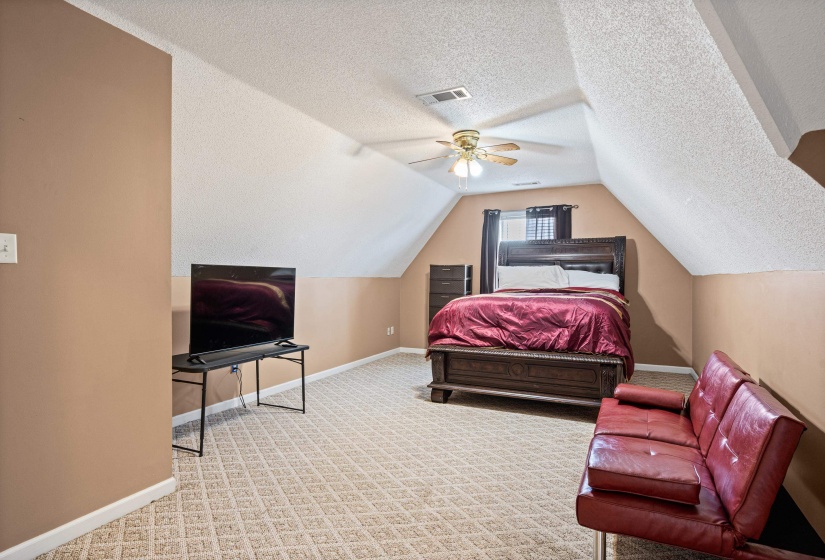 Spacious room featuring vaulted ceilings, patterned carpet, and a ceiling fan with integrated lighting