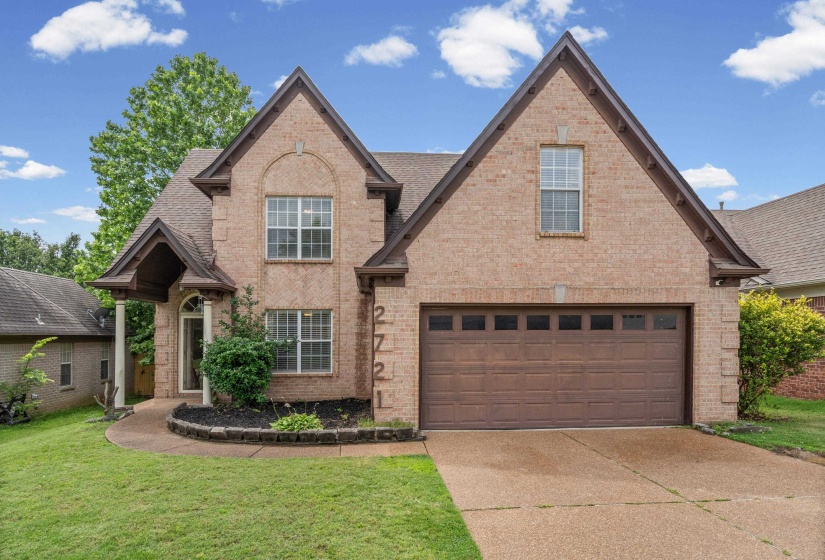 Brick facade home featuring a prominent two-car garage with a brown door
