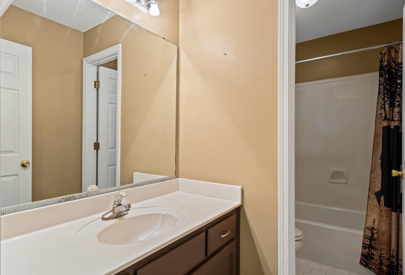 Bathroom vanity featuring a single basin sink, laminate countertop, and wood-finish cabinetry