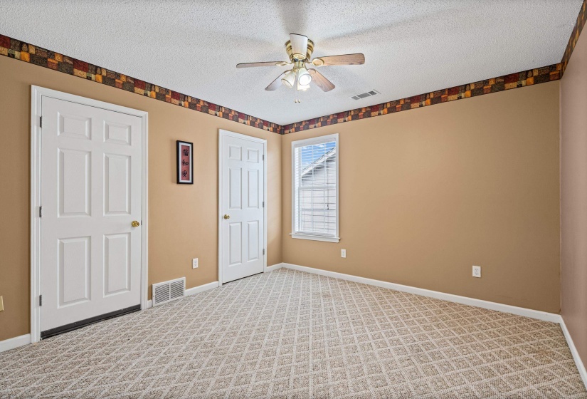 Carpeted room featuring a ceiling fan with integrated lighting, a double-hung window, and two paneled doors