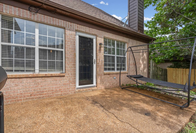 Outdoor patio featuring a textured concrete surface, brick exterior, and a white framed glass door