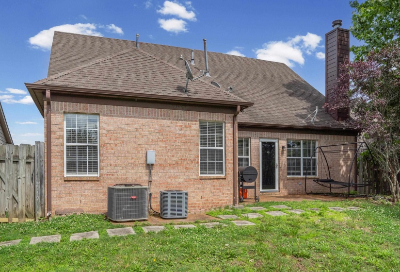 Brick exterior featuring a gabled roofline, multiple windows with white frames, a rear entry door, and a brown-toned chimney