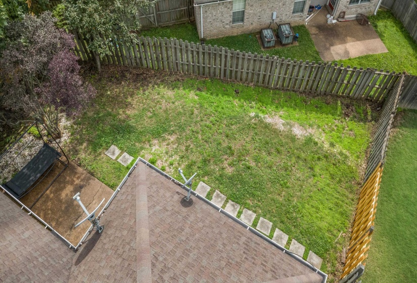 Fenced backyard featuring a mix of mature trees and grassy areas