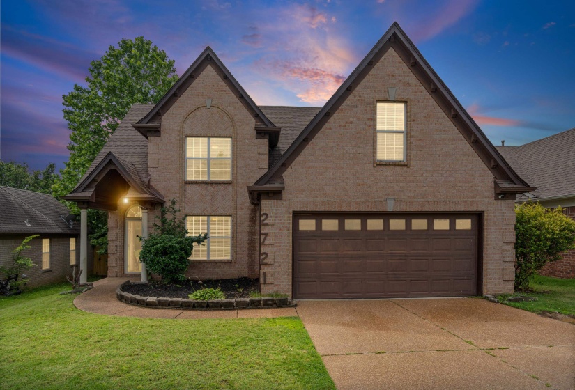 Brick-front residence featuring a two-car garage, covered entry with columns, gabled rooflines, and a concrete driveway