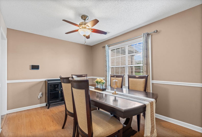Dining area featuring wood-finish flooring, a ceiling fan with integrated lighting, and a single window with blinds