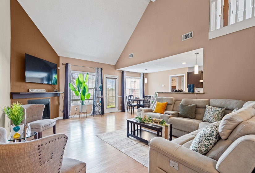 Spacious living area featuring a vaulted ceiling and wood-finish flooring