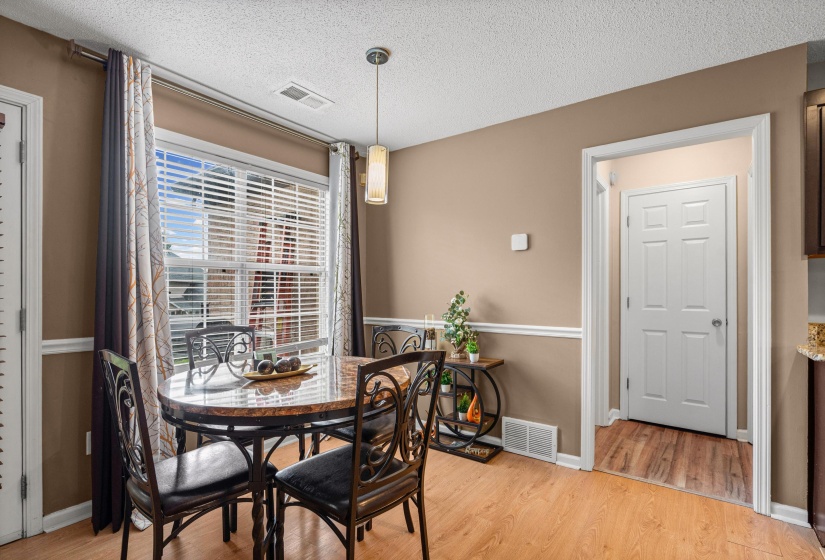 Dining area featuring wood-finish flooring, a large window with horizontal blinds, and a contemporary pendant light fixture