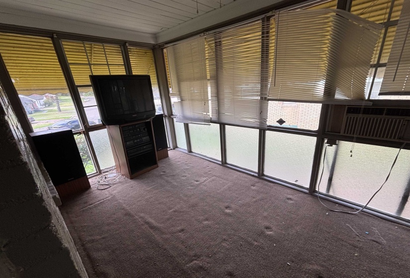 Enclosed porch area featuring extensive window treatments, brown carpeting, and a white paneled ceiling