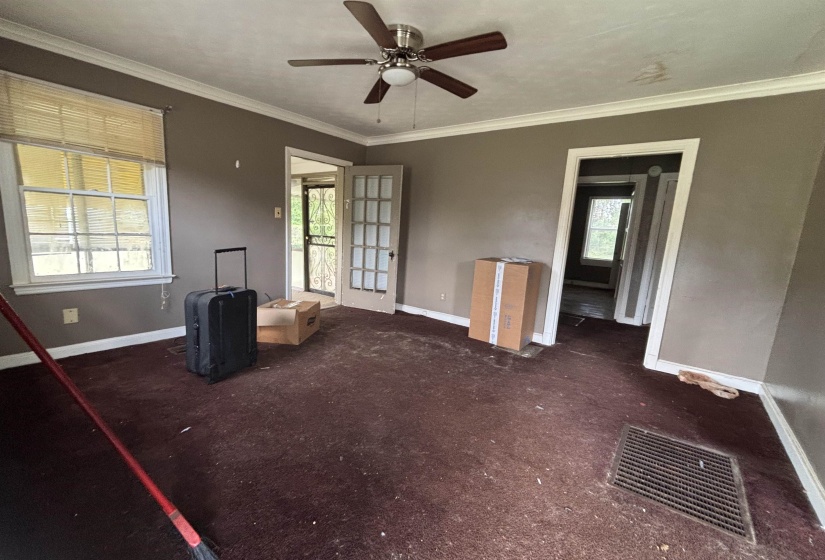 Room featuring a ceiling fan with light fixture, crown molding, and two windows