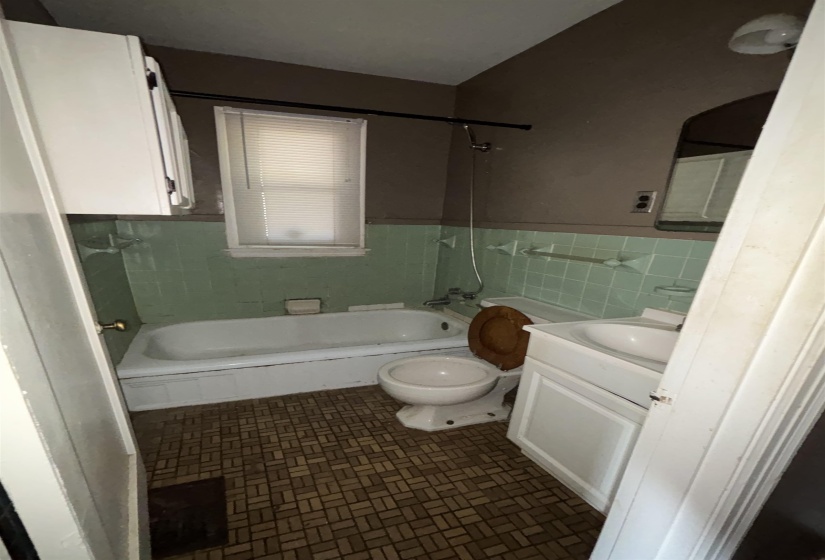 Bathroom featuring a white bathtub, toilet, and vanity with an integrated sink