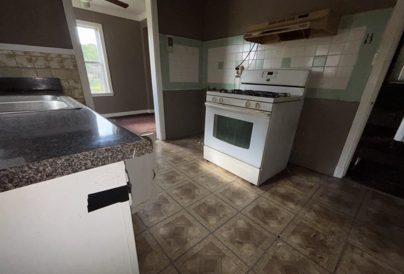 Kitchen with patterned floor tiles, white gas range, and a range hood