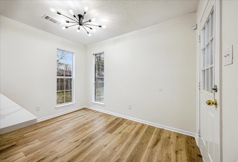 Spare room with light wood-style floors, a chandelier, and a textured ceiling
