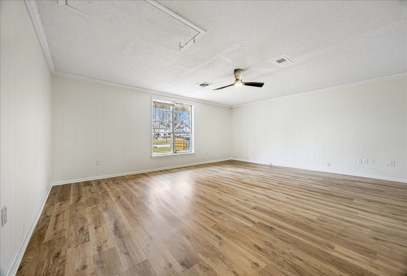 Unfurnished room with attic access, light wood-style floors, ornamental molding, a textured ceiling, and wooden walls