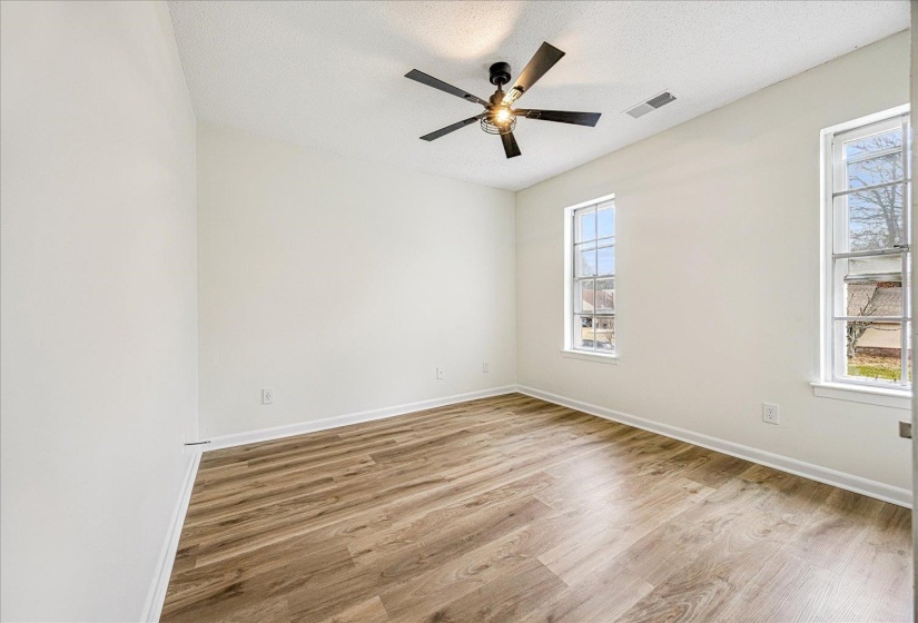 Empty room featuring light wood-type flooring, a textured ceiling, and ceiling fan