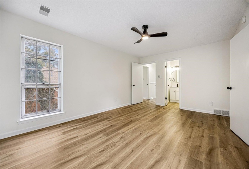 Unfurnished bedroom with a ceiling fan, light wood-style flooring, and ensuite bath