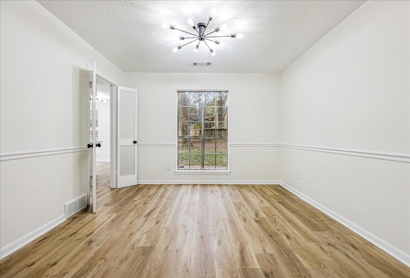 Unfurnished room with a chandelier, light wood-type flooring, and a textured ceiling