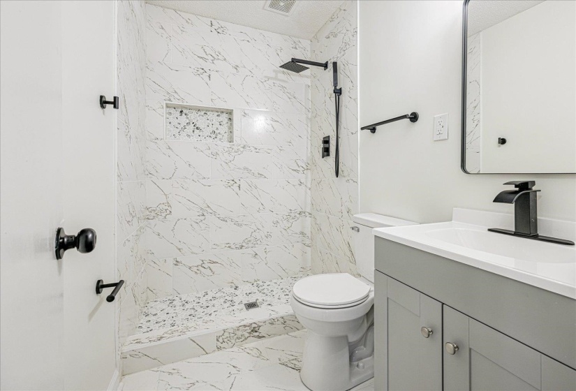 Full bathroom with a marble finish shower, vanity, and light marble finish floors