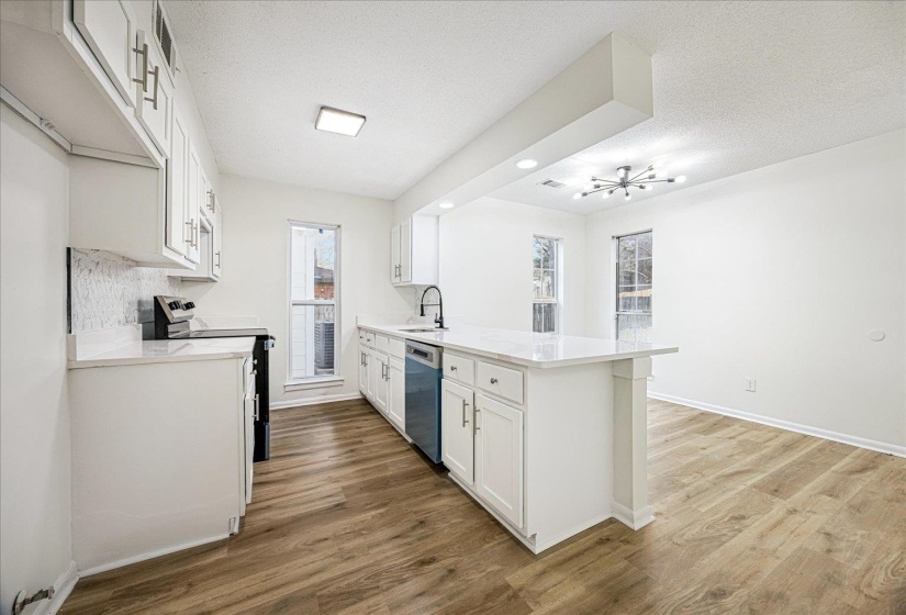 Kitchen featuring white cabinetry, stainless steel appliances, a peninsula, a textured ceiling, and dark wood-style floors