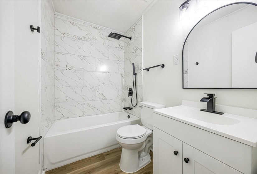 Bathroom featuring  shower combination, vanity, light wood-style floors, and a textured ceiling