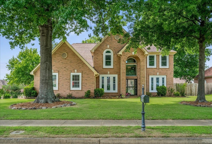 Two-story brick facade featuring an arched entryway, multiple double-hung windows with white trim, and a gabled roofline