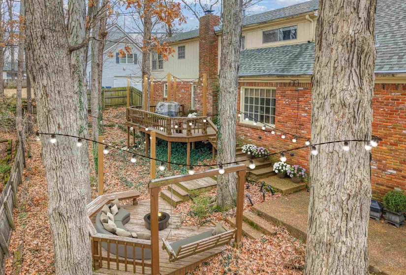 Multi-level rear deck with built-in seating, a fire pit, and string lighting