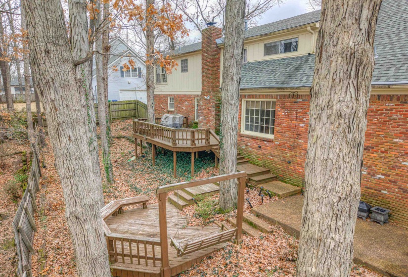 Rear view of house featuring a wooden deck, roof with shingles, a chimney, and brick siding