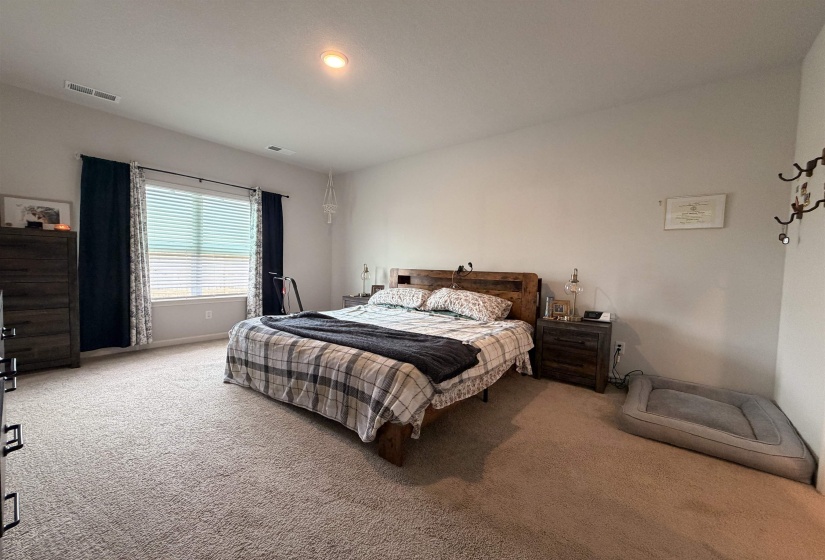 Spacious room with light neutral wall tones, recessed ceiling lighting, and a broad window with horizontal blinds