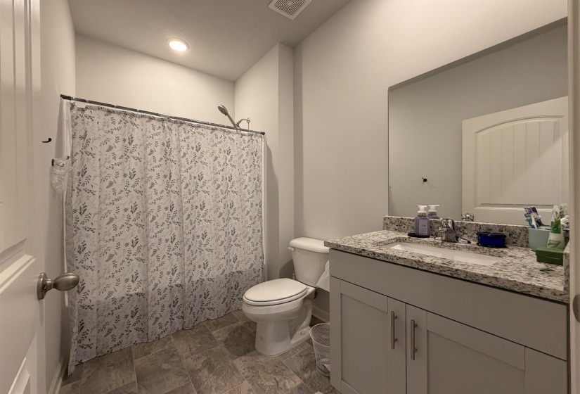 Bathroom featuring a shower-tub combination, single vanity with a stone-look countertop, integrated sink, and undermount cabinetry
