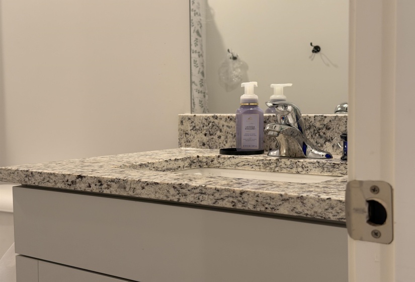 Vanity with a speckled countertop, integrated sink, and polished chrome faucet