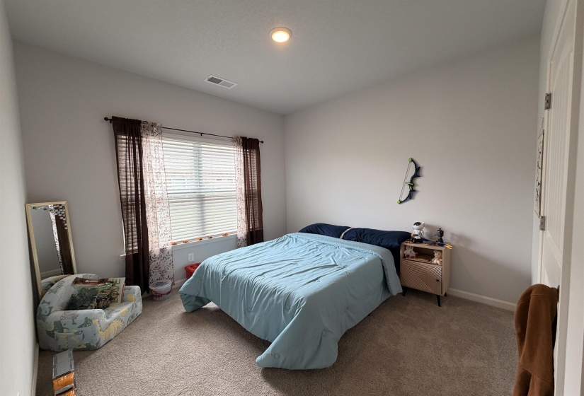 Carpeted room featuring a window with blinds, recessed ceiling lighting, and a white paneled door
