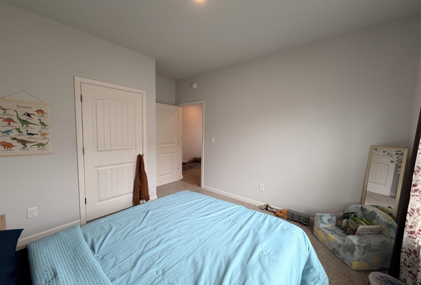Neutral wall paint, plush carpet flooring, two-panel interior doors, and white baseboards