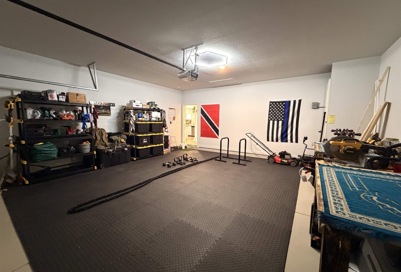 Spacious garage featuring a durable rubberized floor, overhead lighting, and abundant wall space