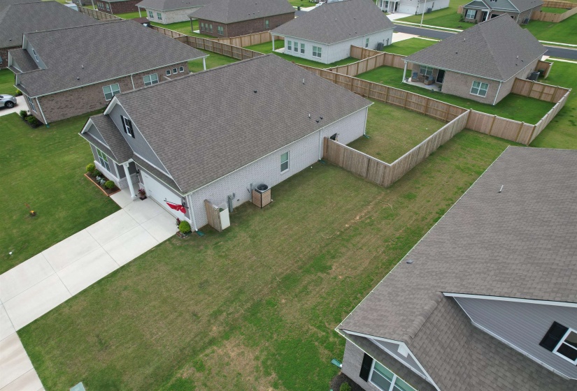 Contemporary residence with dark shingle roofing and light siding, featuring a concrete driveway, attached garage, and a fully fenced backyard