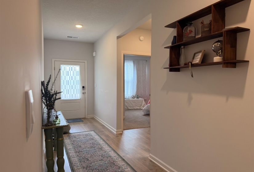 Inviting entryway featuring a paneled front door with decorative privacy glass, recessed lighting, and wood-finish flooring extending into the interior