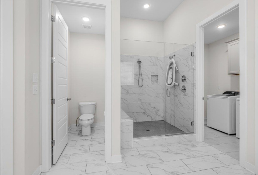 Spacious bathroom featuring large format floor tiling and a frameless glass shower enclosure