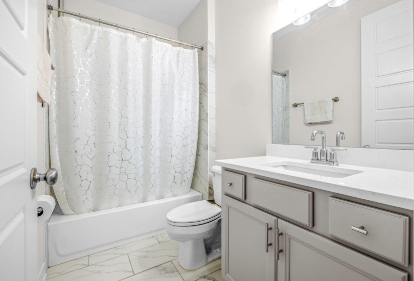 Bathroom featuring a single vanity with stone-finish countertop, undermount sink, and chrome fixtures