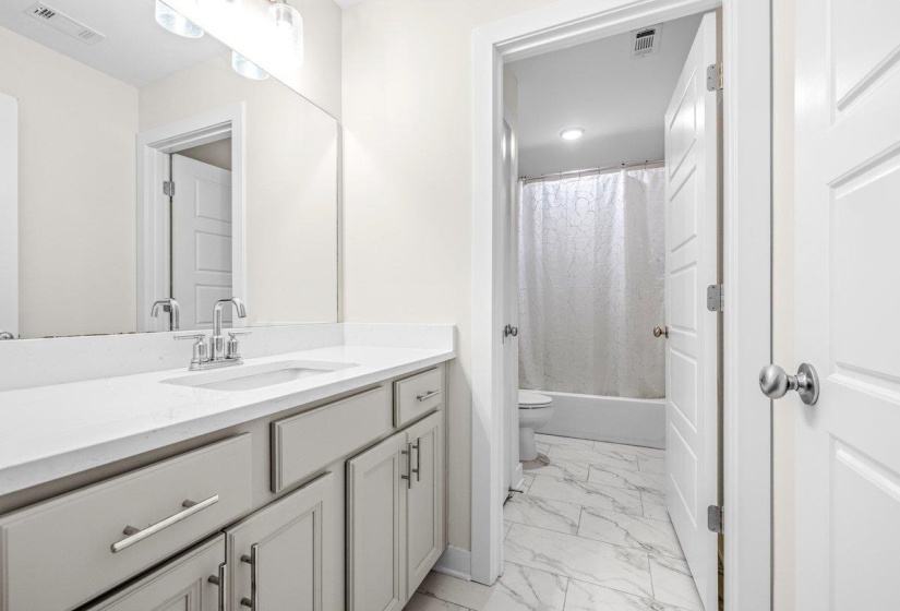 Bathroom featuring a light-toned vanity with a built-in sink, expansive countertop, and chrome fixtures