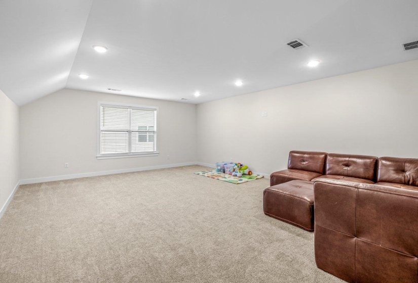 Spacious room featuring neutral carpeting, recessed lighting, white walls, and a window with blinds