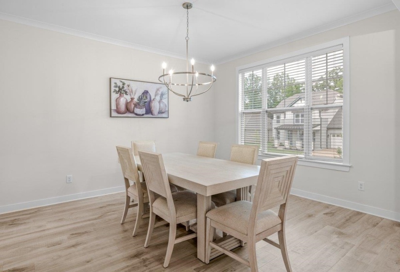 Dining area featuring wood-finish flooring, a large window with blinds, and white crown molding