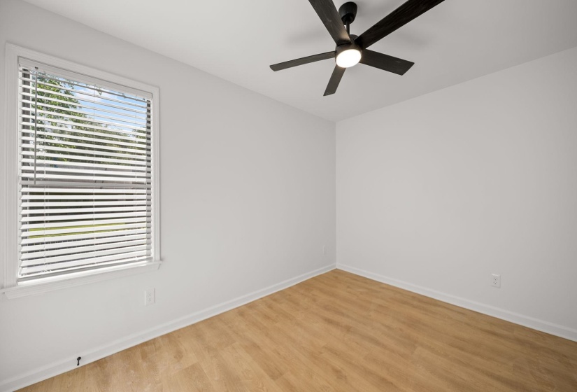 Room featuring wood-finish flooring, white walls, and a window with blinds