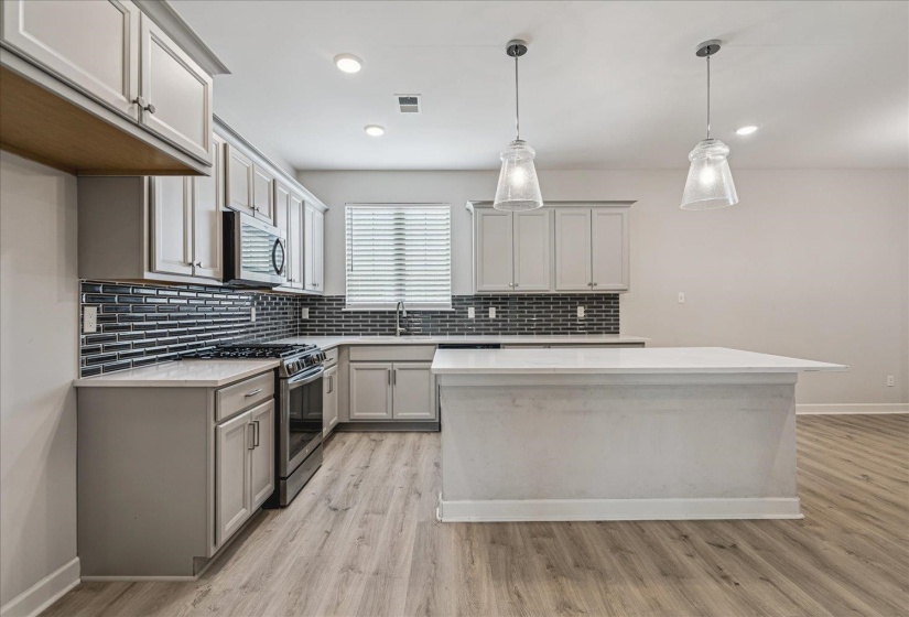 Kitchen featuring gray shaker-style cabinetry, a contrasting dark subway tile backsplash, and light countertops